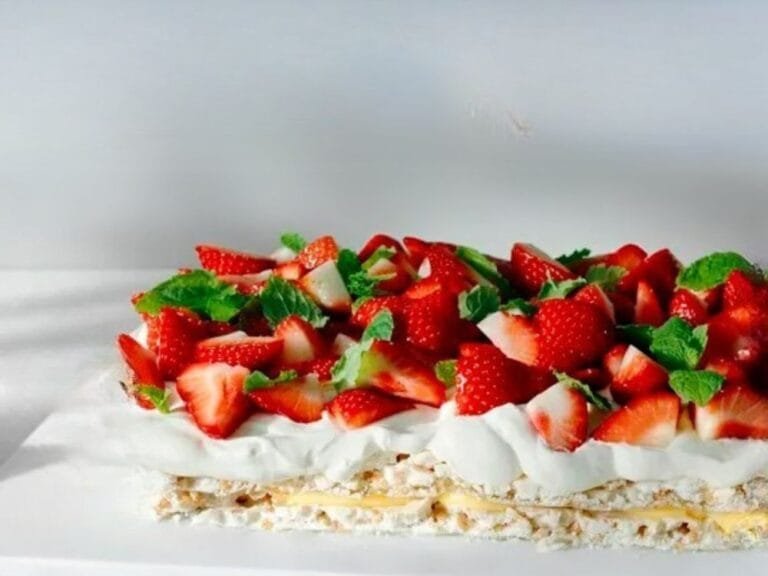Rice Krispies cake with whipped cream, lemon cream, fresh strawberries, and mint leaves.