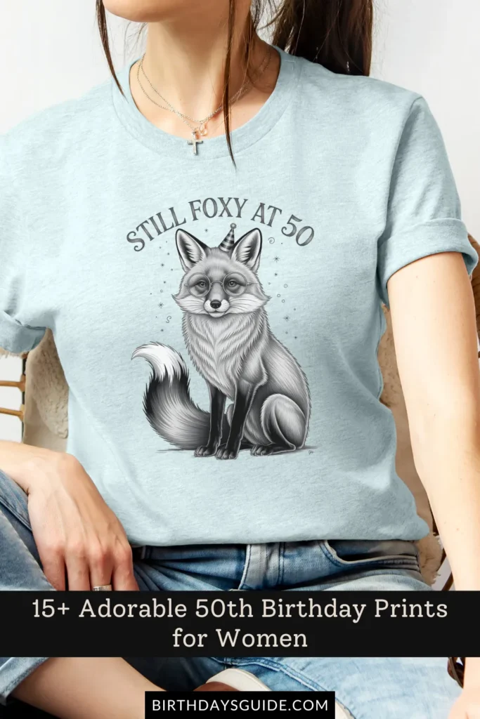 A light blue birthday t-shirt featuring an adorable fox wearing a party hat, with the phrase "Still Foxy at 50" in a whimsical font.