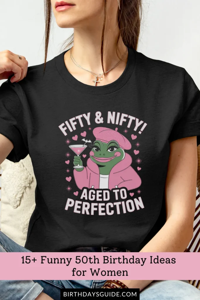 A black birthday t-shirt with a trendy, stylish frog illustration wearing a pink beret and holding a martini glass, with the phrase "Fifty & Nifty! Aged to Perfection.