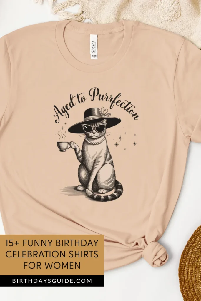 A beige birthday t-shirt featuring a sophisticated cat wearing sunglasses, a hat, and pearls, holding a cup of tea. The phrase "Aged to Purrfection" is written in stylish script.
